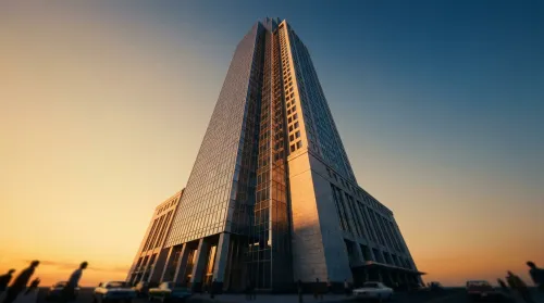 A single modern glass-and-stone financial tower rising against a golden-hour sky, one of the largest finance companies